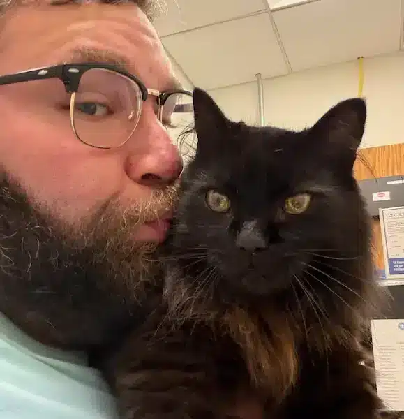 Gabe kissing Tommy the cat during TSA security screening with Cabin Companions
