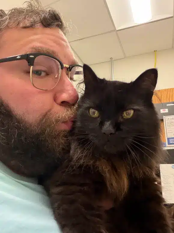 Gabe kissing Tommy the cat during TSA security screening with Cabin Companions